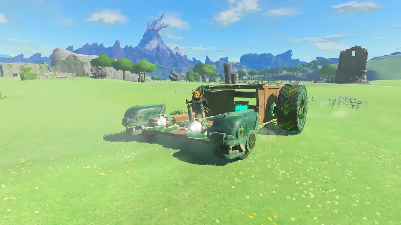 Link building a Zonai vehicle with fans and wheels on a grassy field in Tears of the Kingdom